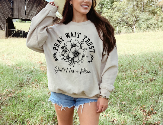 Woman wearing the Pray Wait Trust Crew sweatshirt, showcasing a black and white floral design, embodying casual comfort with a ribbed collar and loose fit.