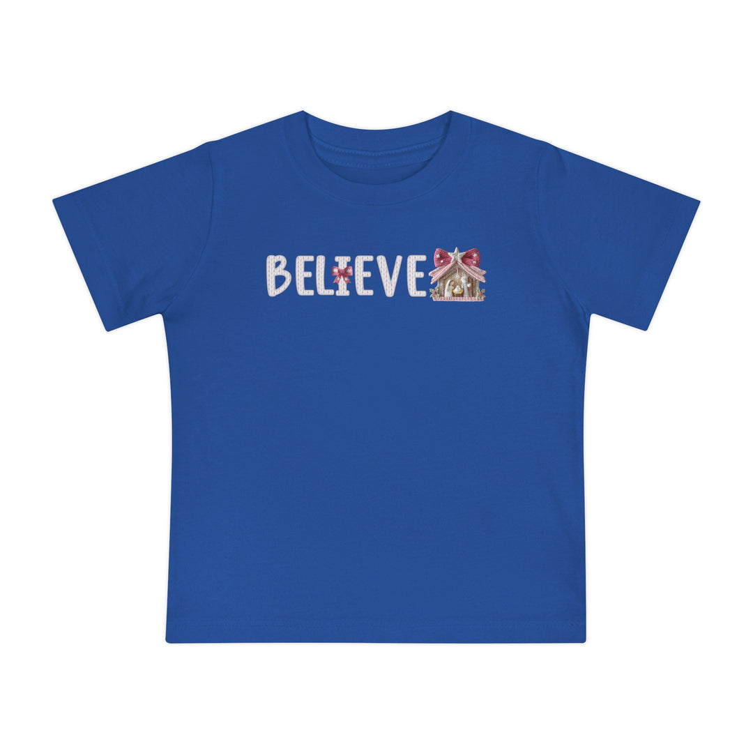Believe Baby Tee: Bright blue T-shirt featuring BELIEVE with a gingerbread-house motif, designed for comfort and durability in soft, pre-shrunk cotton.