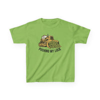 Light-green Pushing My Luck kids tee with a bulldozer graphic pushing shamrocks, ideal for everyday wear. Made from soft, durable US cotton.