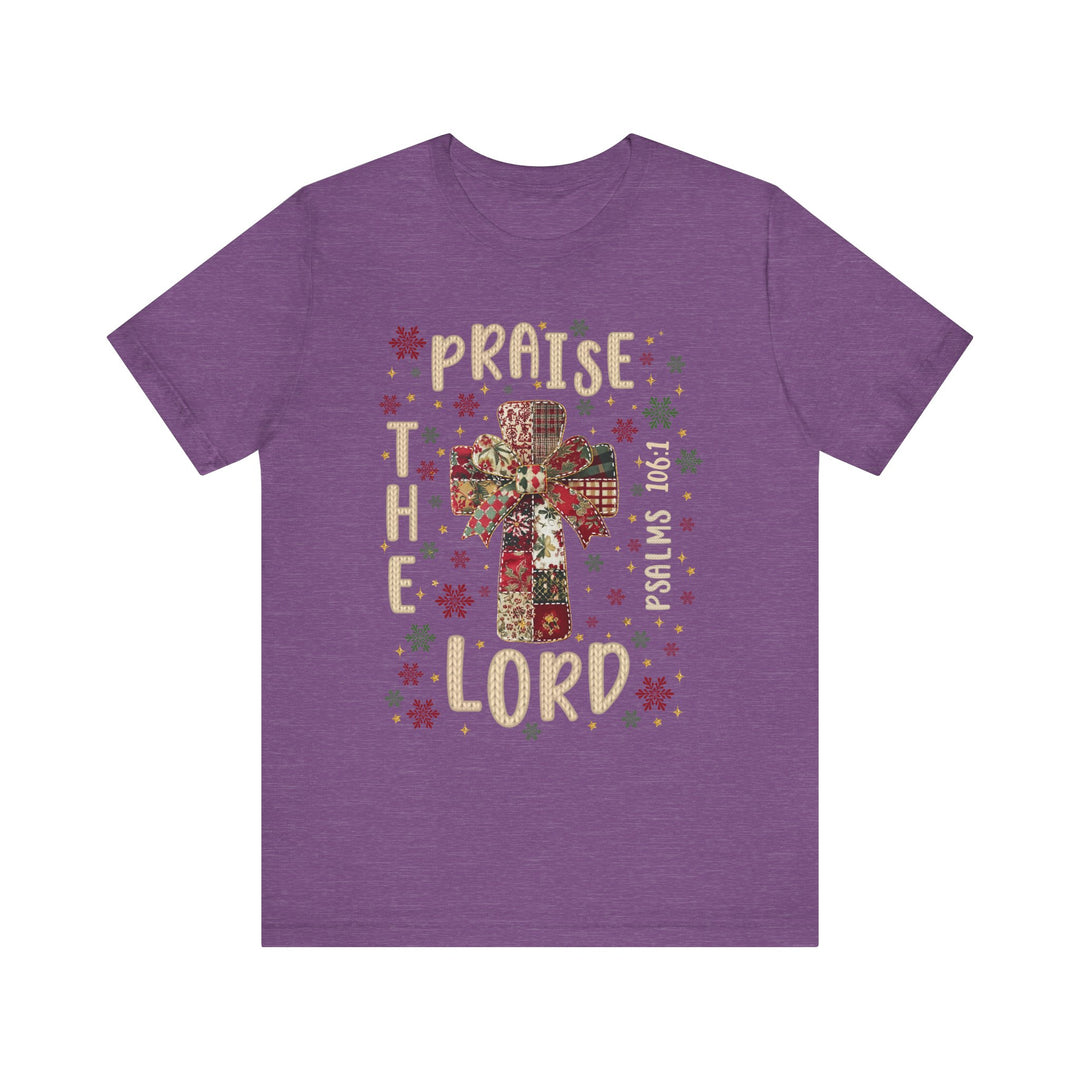 Praise the Lord Tee with patchwork cross, bow, and snowflake motifs; features Bible reference Psalms 106:1, combining faith-inspired design with comfortable unisex fit.