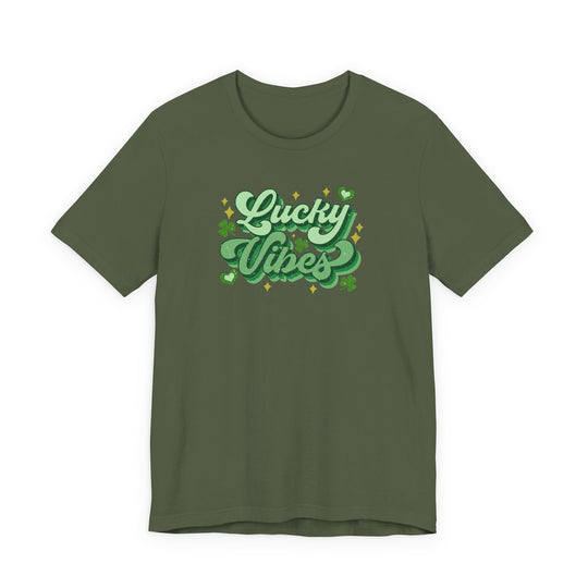 Olive-green Good Day Lucky Day Tee with Lucky Vibes slogan, sparkles, hearts, and shamrocks, offering a festive St. Patrick’s Day look in soft cotton.