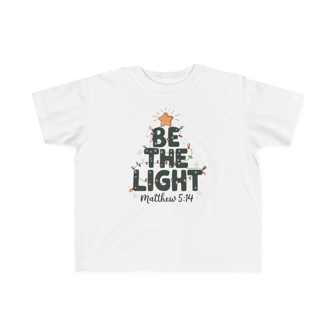 Be the Light Toddler Tee with BE THE LIGHT graphic in tree shape, adorned with Christmas lights and Matthew 5:14 reference, offers softness and durability for toddlers.