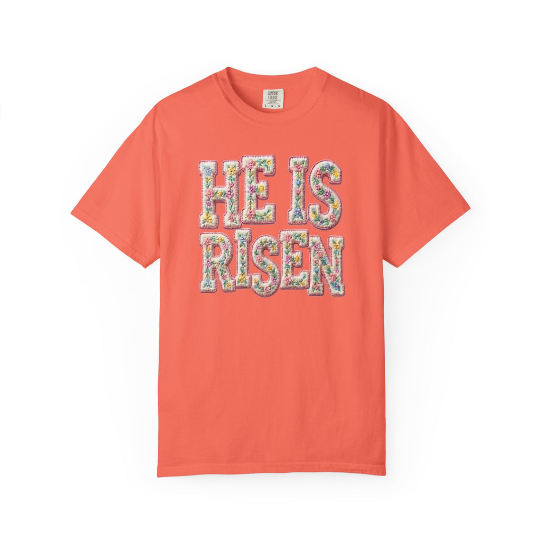 Coral He is Risen Tee with multicolored floral text, unisex fit, garment-dyed, 80% ring-spun cotton, 20% polyester, from Faith Family Designs.