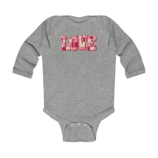 Gray long-sleeve Love onesie with pink and red textured letters, featuring snap closures and ribbed edges, ideal for infants. Soft, durable cotton blend.