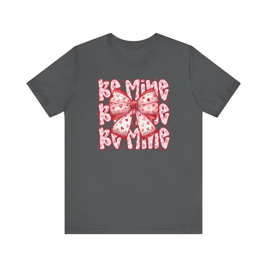 Be Mine Tee featuring a playful pink ribbon and Be Mine text with heart accents on a dark charcoal-gray T-shirt, perfect for Valentine's Day.
