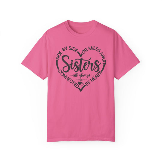 Sisters At Heart Tee: A pink Gildan t-shirt featuring black text, crafted from 100% ring-spun cotton with a relaxed fit and durable double-needle stitching.