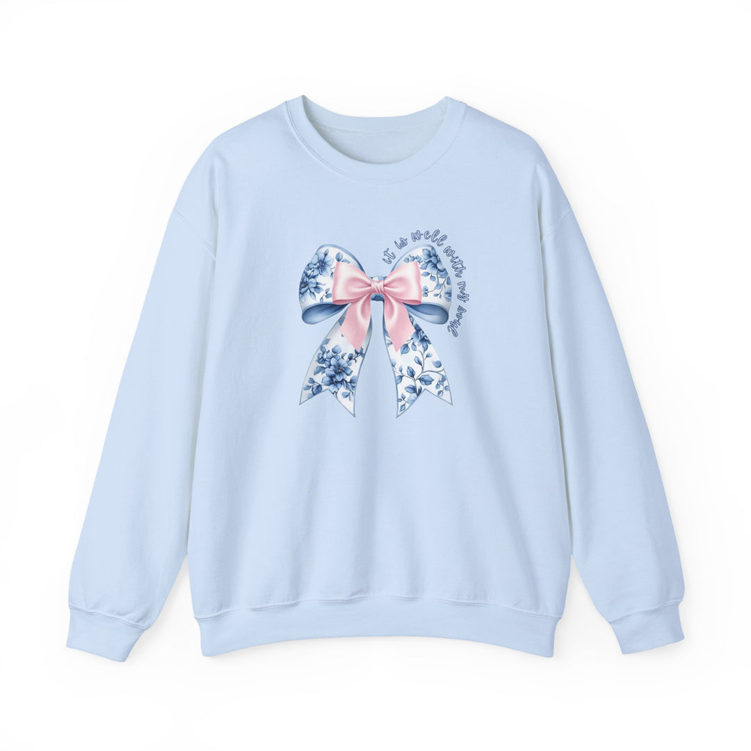 Light-blue crewneck sweatshirt with floral bow graphic and cursive text it is well with my soul, epitomizing comfort and style from Faith Family Designs.