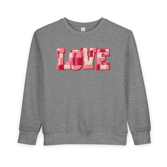 Heather-gray toddler crewneck sweatshirt with LOVE in pink, red, and off-white chenille-style letters. Cozy, durable, and designed for warmth and comfort.