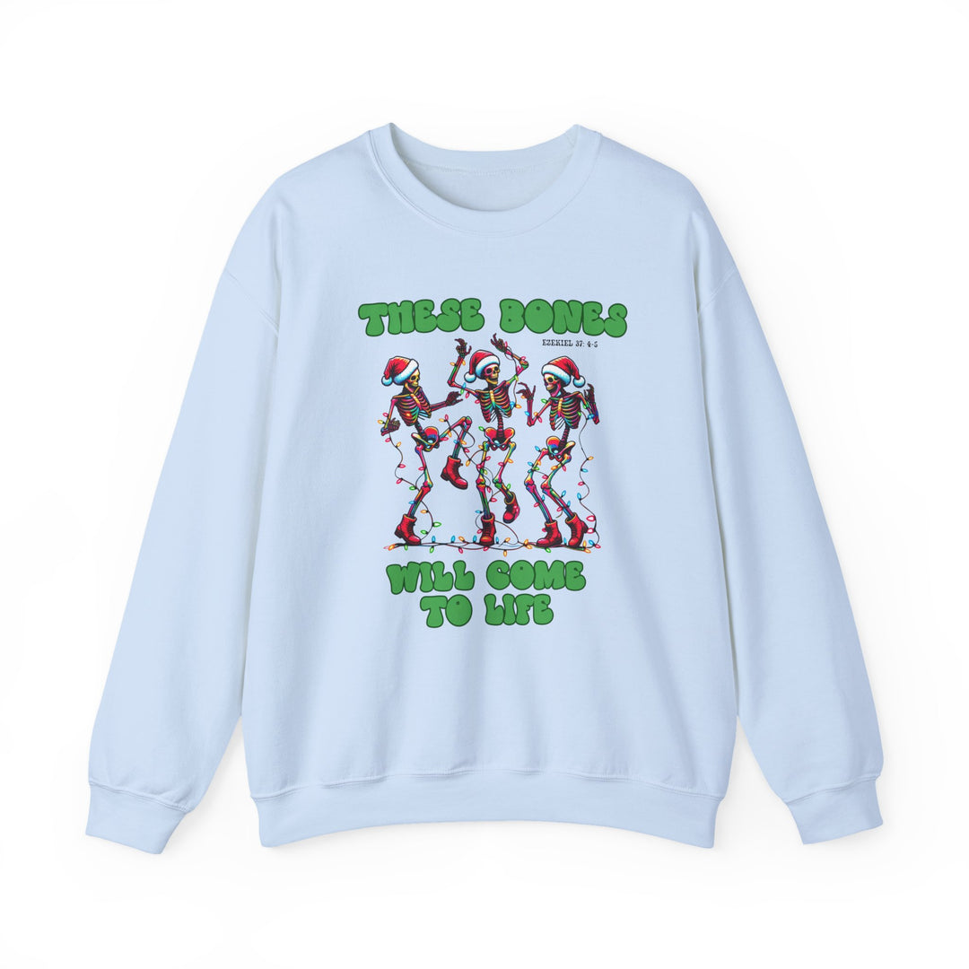 Light-blue crewneck sweatshirt with festive cartoon skeletons in Santa hats, tangled in Christmas lights, and text THESE BONES WILL COME TO LIFE, referencing Ezekiel 37:4–5.