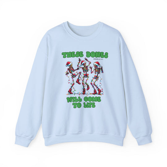 Light-blue crewneck sweatshirt with festive cartoon skeletons in Santa hats, tangled in Christmas lights, and text THESE BONES WILL COME TO LIFE, referencing Ezekiel 37:4–5.