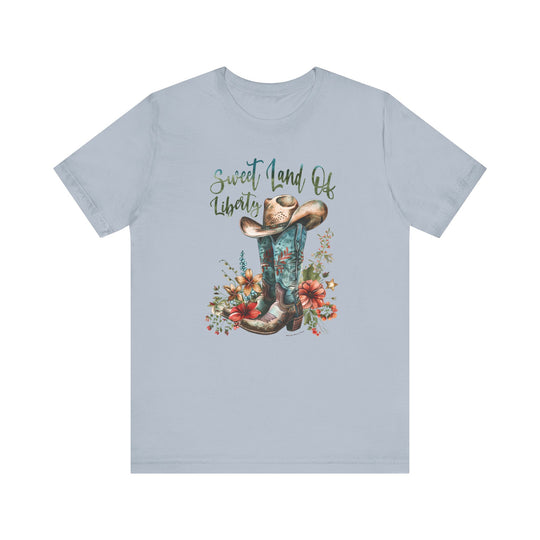 A Sweet Land of Liberty Tee featuring a cowboy hat and boots design on a soft cotton jersey. Unisex fit with ribbed knit collars, taping on shoulders, and tear-away label. Sizes XS to 3XL.