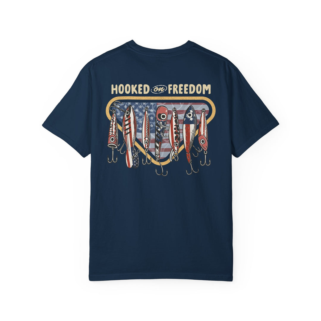 Back of Hooked on Freedom Tee featuring HOOKED on FREEDOM text and vintage fishing lures with stars-and-stripes design over a subtle American flag pattern.