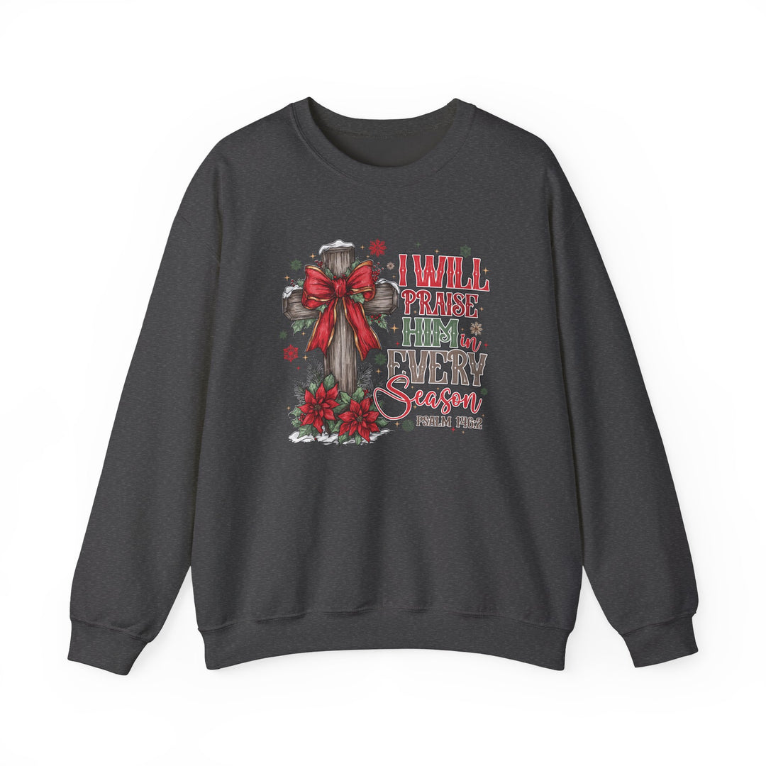 Dark-charcoal crewneck sweatshirt with wooden cross, red bow, poinsettias, and text “Praise Him in Every Season,” reflecting a Christian Christmas theme.