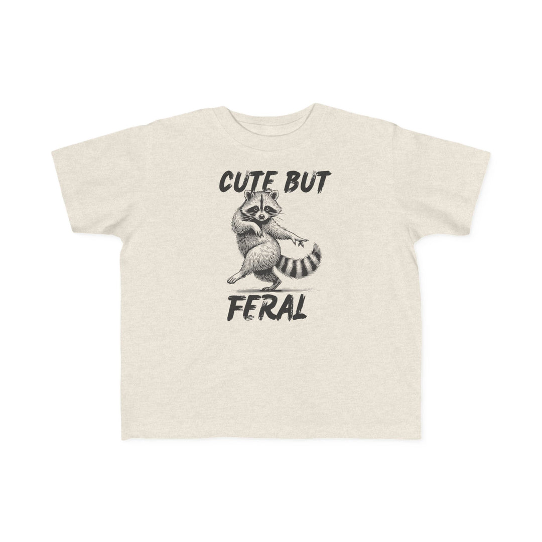 Cute but Feral Toddler Tee featuring a playful raccoon illustration with bold text, designed for comfort with soft, durable cotton, perfect for toddler adventures.