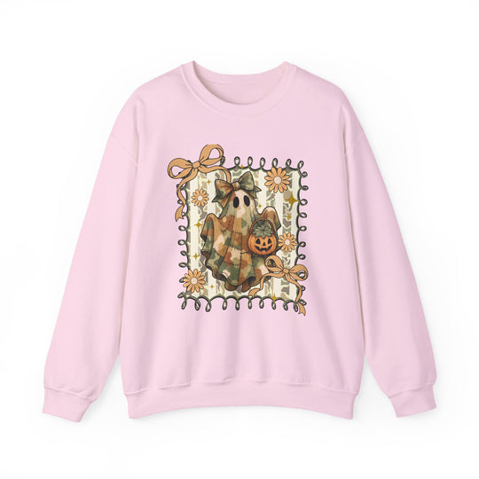 Pale-pink crewneck sweatshirt featuring a whimsical Halloween motif: a camo-toned ghost with a bow and jack-o'-lantern bucket, surrounded by playful ribbons and daisies.