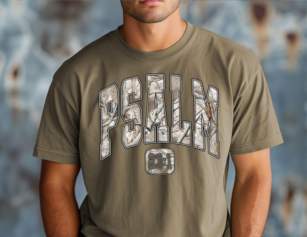 Man wearing Camo Psalm 23 Tee featuring camo-patterned PSALM text and 23:1 boxed underneath on an olive-green T-shirt from Faith Family Designs.