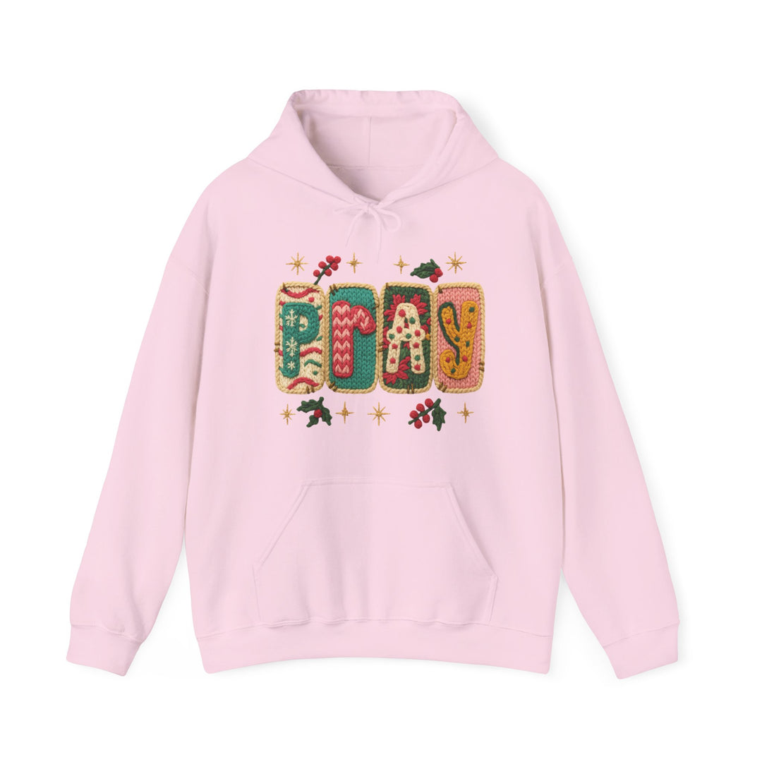 Light pink Pray hoodie with festive knitted graphic, holly motifs, kangaroo pocket, and drawstring hood, embodying cozy holiday vibes.