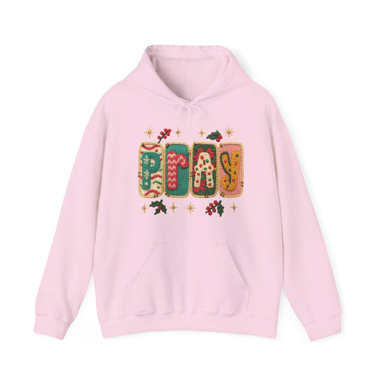 Light pink Pray hoodie with festive knitted graphic, holly motifs, kangaroo pocket, and drawstring hood, embodying cozy holiday vibes.