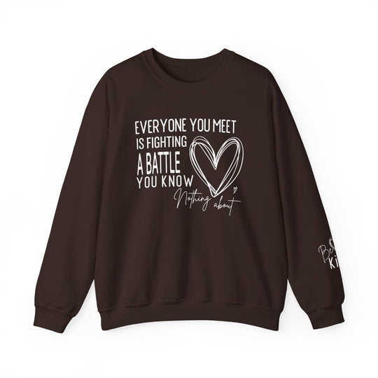 Dark-brown crewneck sweatshirt with motivational text Everyone you meet is fighting a battle you know nothing about and a heart sketch, featuring Be Kind on the sleeve.