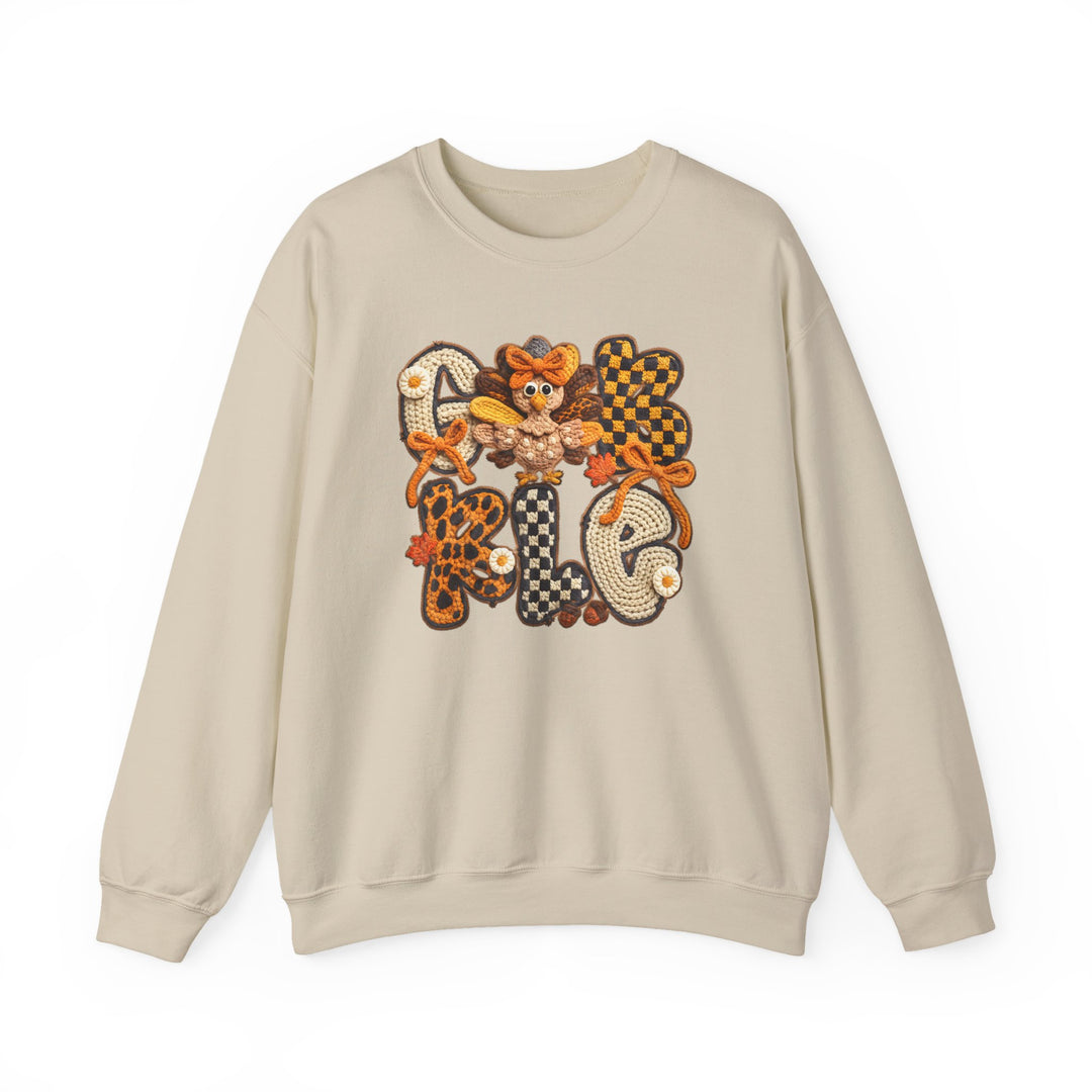 Light-beige crewneck sweatshirt with GOBBLE in crocheted-style patches, featuring autumn-themed designs and a cartoon turkey for a festive, Thanksgiving-inspired look.