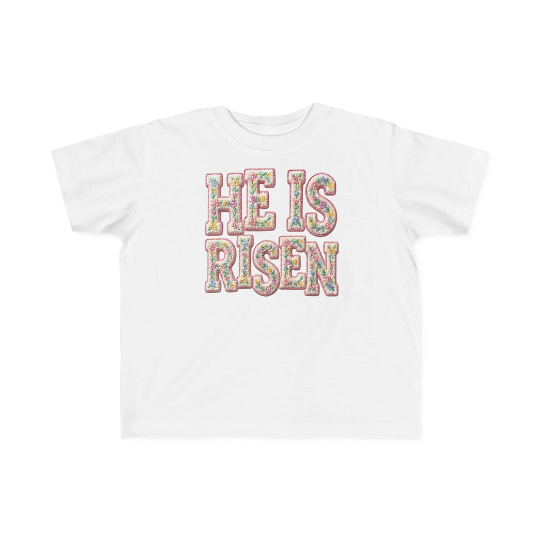 He is Risen Toddler Tee featuring pastel floral-patterned lettering, ideal for toddlers' comfort with soft cotton fabric.