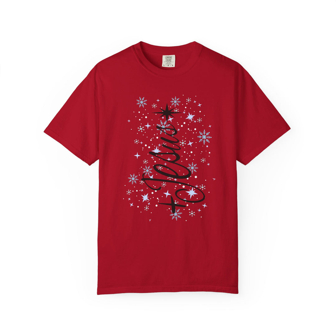 Jesus Tree Tee features a red T-shirt with a festive holiday design in stylized cursive, star topper, snowflakes, and starbursts.