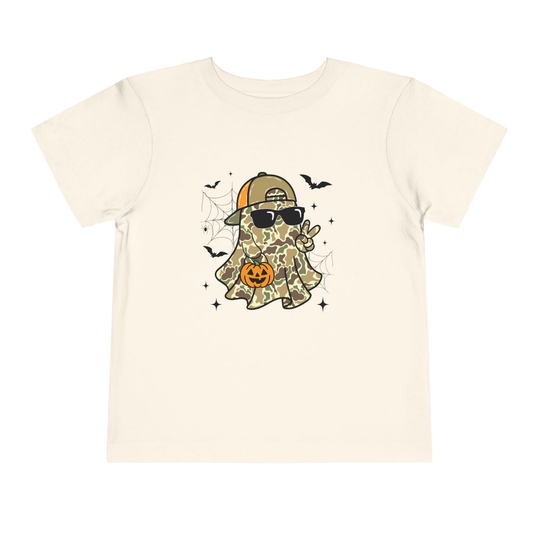 Candy Ghost Toddler Tee featuring a cartoon ghost in camouflage with sunglasses and baseball cap, surrounded by bats and spider-webs, holding a peace sign and jack-o-lantern.