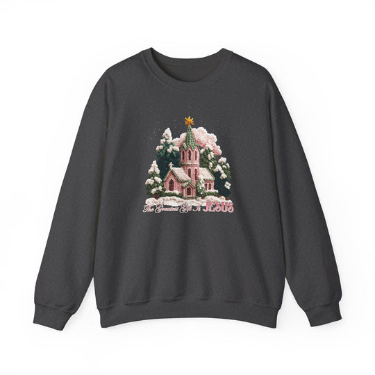 Gift is Jesus Crew sweatshirt with festive winter scene, pink church, snow-laden trees, and The Greatest Gift Is JESUS phrase in script on charcoal-gray fabric.