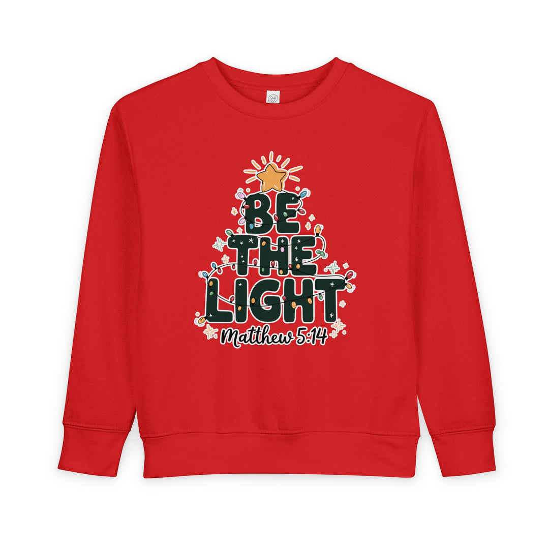 Be the Light Toddler Crew sweatshirt, featuring a holiday-style Christmas tree graphic with BE THE LIGHT, colorful lights, and Matthew 5:14 reference, highlighting Faith Family Designs' unique style.