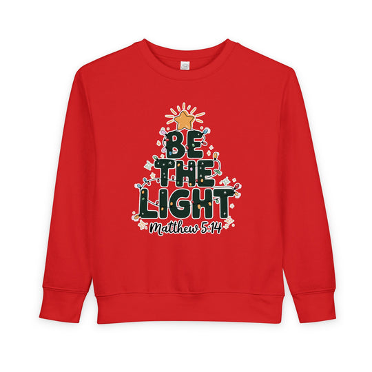 Be the Light Toddler Crew sweatshirt, featuring a holiday-style Christmas tree graphic with BE THE LIGHT, colorful lights, and Matthew 5:14 reference, highlighting Faith Family Designs' unique style.