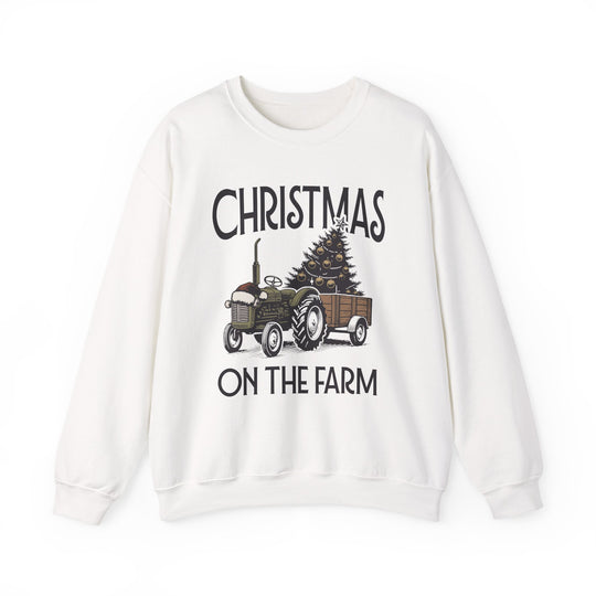 White sweatshirt featuring Christmas on the Farm design with a green tractor towing a decorated Christmas tree, ideal for cozy, festive wear.