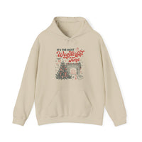 Light-beige Most Wonderful Time of the Year hoodie features festive vintage-style print with Christmas tree, fireplace, and gifts, offering cozy warmth and practical kangaroo pocket.