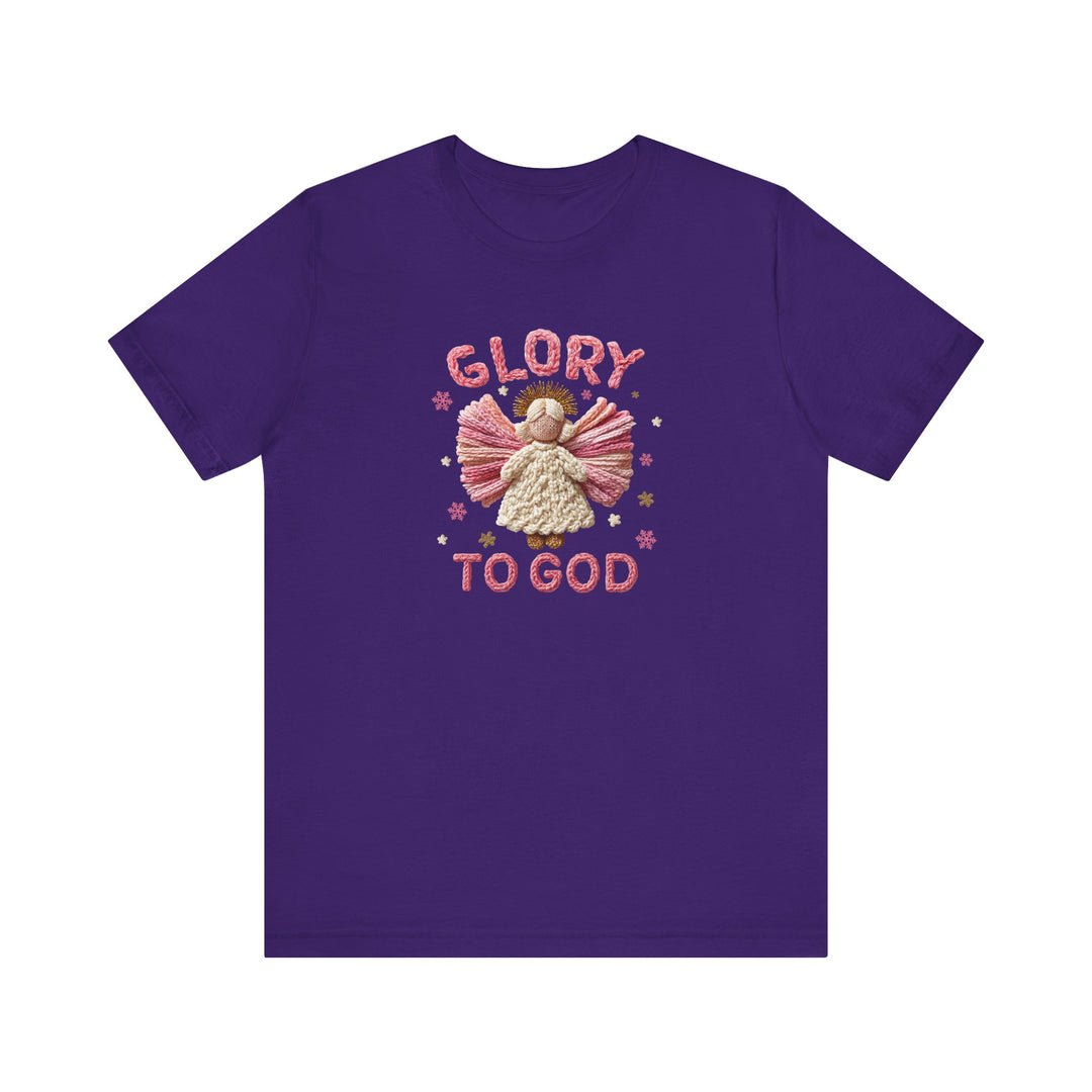 Glory to God Tee featuring a yarn-style angel with pink wings, cream dress, golden halo, surrounded by stars and snowflakes, in a soft cotton fabric.