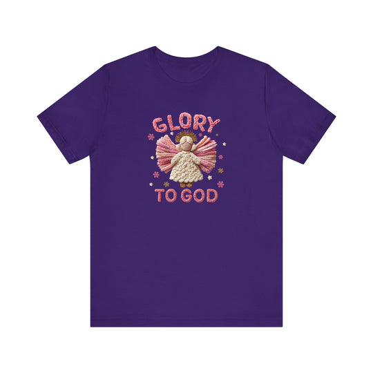 Glory to God Tee featuring a yarn-style angel with pink wings, cream dress, golden halo, surrounded by stars and snowflakes, in a soft cotton fabric.