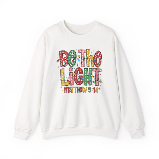 Be the Light Crew sweatshirt featuring a colorful holiday graphic with 'Be the Light' and 'Matthew 5:14', offering cozy comfort and ethical craftsmanship.