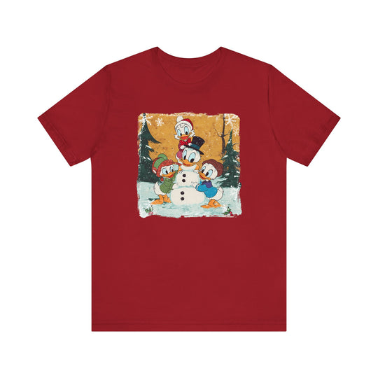 Duck Snowmen Tee features Donald Duck and nephews building a snowman in a snowy scene, capturing holiday charm. Soft, unisex fit with durable cotton.