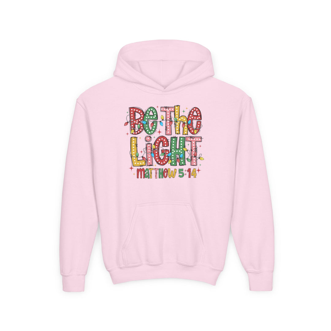 Light-pink youth hoodie with Be the Light slogan in colorful marquee-style letters, featuring Matthew 5:14 below, designed by Faith Family Designs.
