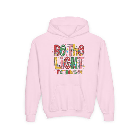 Light-pink youth hoodie with Be the Light slogan in colorful marquee-style letters, featuring Matthew 5:14 below, designed by Faith Family Designs.