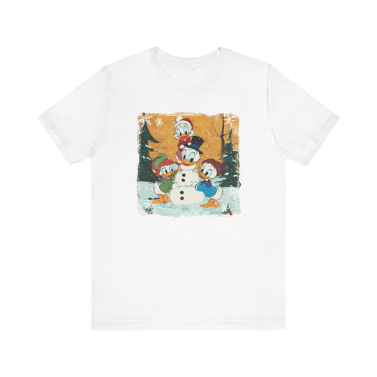 Duck Snowmen Tee: A white T-shirt featuring a whimsical winter scene with ducklings building a Donald Duck snowman in a snowy forest, perfect for fans of unique graphic tees.