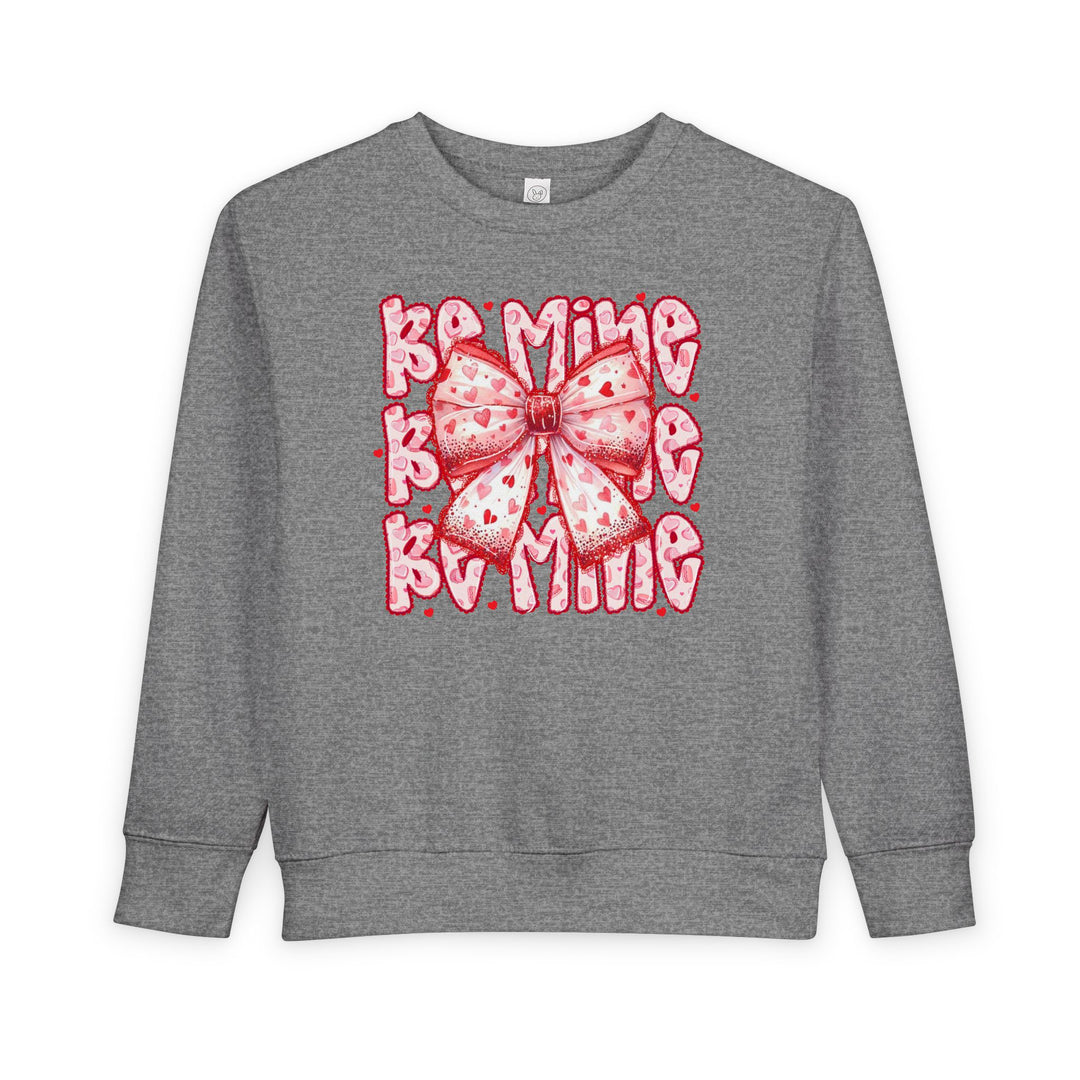Be Mine Toddler Crew: Heather-gray sweatshirt with a pink-and-red heart-patterned bow and playful Bling text, offering cozy comfort for toddlers.