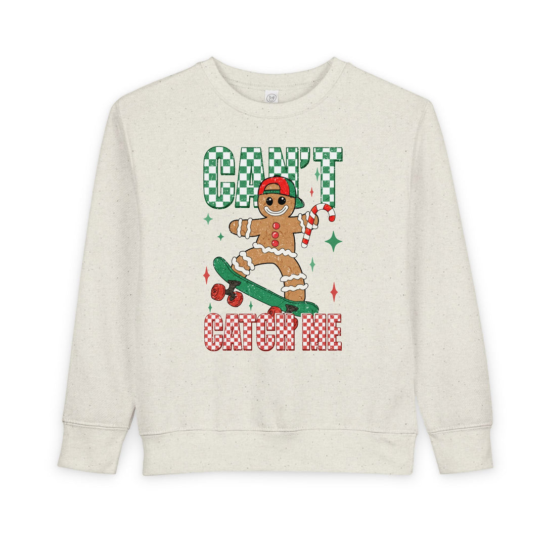Can't Catch Me Toddler Crew sweatshirt featuring a gingerbread cookie on a skateboard, with festive green and red checker-patterned text and starburst accents.