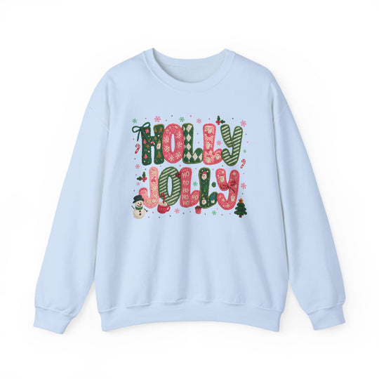 Light-blue crewneck sweatshirt featuring HOLLY JOLLY in festive red-and-green designs with snowflakes, holly, snowman, and Christmas tree accents. Cozy, durable blend.