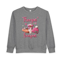 Freezin Season Toddler Crew: Heather-gray sweatshirt with playful winter motifs—pink lettering, hot-drink cup, slippers, beanie, and snowflakes—crafted for warmth and comfort.