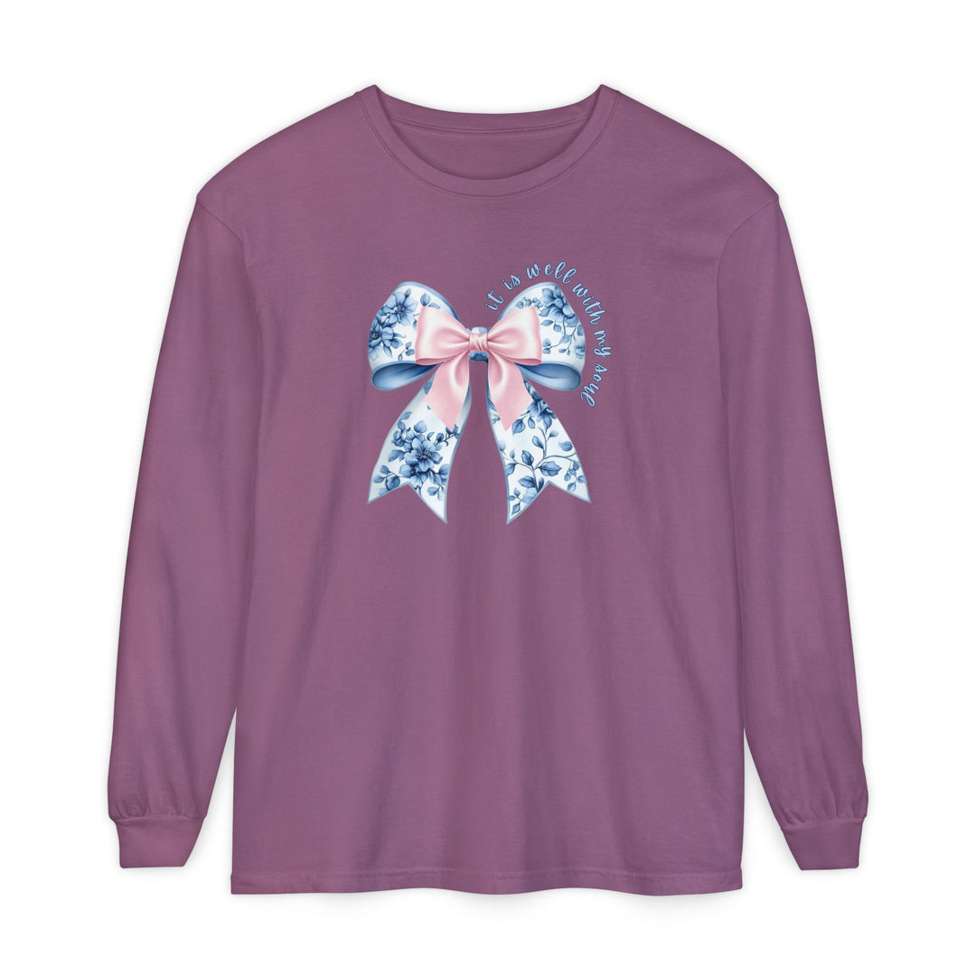 It is Well With My Soul Long Sleeve Tee featuring a floral bow and script on a muted purple background, offering comfort with 100% ring-spun cotton.