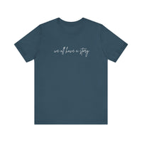 We all have a Story Tee: blue shirt with white text, classic unisex design, soft cotton, ribbed knit collar, and tapered shoulders for optimal fit.