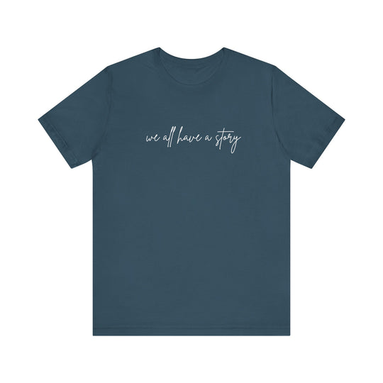 We all have a Story Tee: blue shirt with white text, classic unisex design, soft cotton, ribbed knit collar, and tapered shoulders for optimal fit.