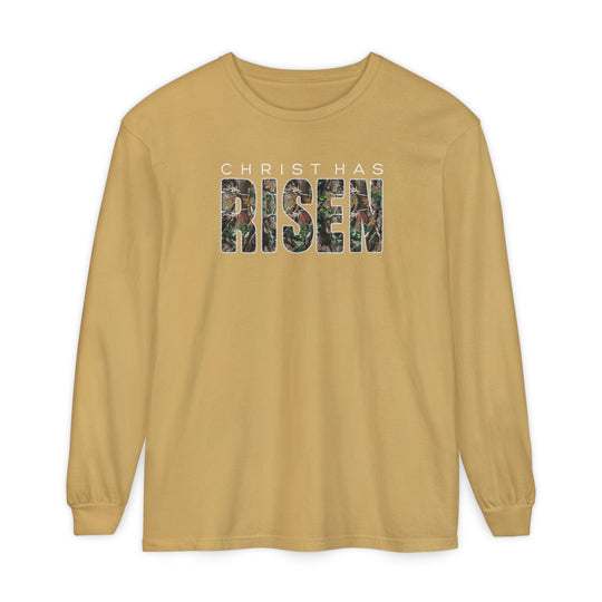 Mustard-gold long-sleeve tee with CHRIST HAS RISEN in white block letters and camouflage pattern, made of 100% ring-spun cotton for comfort.
