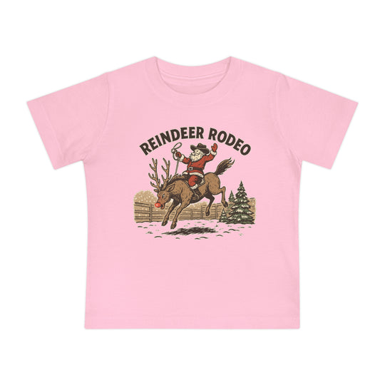 Reindeer Rodeo Baby Tee features Santa as a rodeo rider on a reindeer, with REINDEER RODEO text, ideal for stylish first steps in soft, durable cotton.