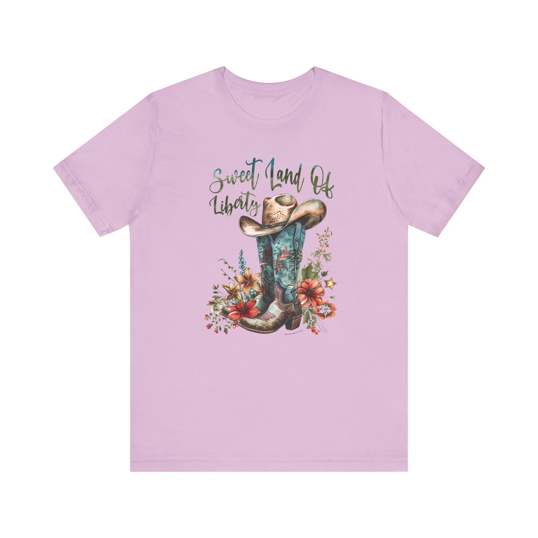 A Sweet Land of Liberty Tee, featuring cowboy boots, a hat, and flowers. Unisex jersey tee with ribbed knit collars, taping on shoulders, and Airlume combed cotton. Retail fit, tear-away label, true to size.