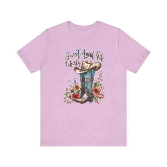 A Sweet Land of Liberty Tee, featuring cowboy boots, a hat, and flowers. Unisex jersey tee with ribbed knit collars, taping on shoulders, and Airlume combed cotton. Retail fit, tear-away label, true to size.